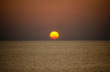 Phuket, Tayland 'da okyanusun üzerinde güzel bir gün batımı, durgun suya yansıyan renkli gökyüzü. Canlı turuncu ve pembe renkleri olan tropik bir cennet. Seyahat ve tatil temaları için mükemmel..