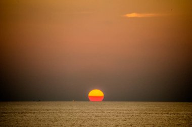 Phuket, Tayland 'da okyanusun üzerinde güzel bir gün batımı, durgun suya yansıyan renkli gökyüzü. Canlı turuncu ve pembe renkleri olan tropik bir cennet. Seyahat ve tatil temaları için mükemmel..