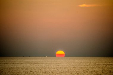 Phuket, Tayland 'da okyanusun üzerinde güzel bir gün batımı, durgun suya yansıyan renkli gökyüzü. Canlı turuncu ve pembe renkleri olan tropik bir cennet. Seyahat ve tatil temaları için mükemmel..