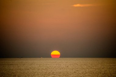 Phuket, Tayland 'da okyanusun üzerinde güzel bir gün batımı, durgun suya yansıyan renkli gökyüzü. Canlı turuncu ve pembe renkleri olan tropik bir cennet. Seyahat ve tatil temaları için mükemmel..