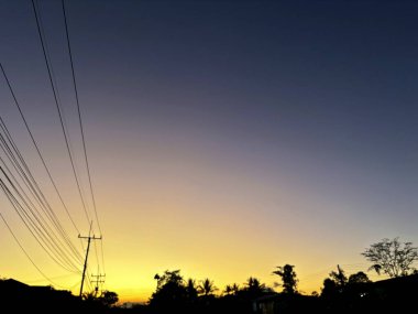 Tayland kırsalında canlı bir günbatımına karşı güç hatlarının silueti