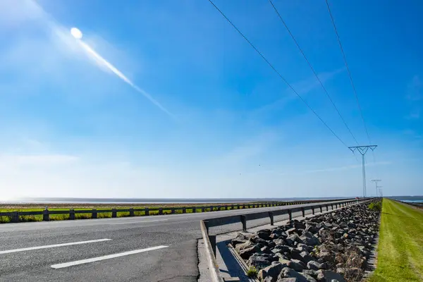 Danimarka 'daki Romo adasına giden mavi gökyüzü ve güneş ışığıyla deniz üzerinde güzel bir köprü.