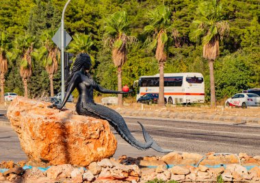 Türkiye 'de 5 Ekim 2019' da Goynuk, Kemer, Antalya şehrinde elinde kırmızı bir nar bulunan güzel, siyah bir deniz kızı heykeli.