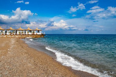 Kemer Türkiye 'deki turkuaz deniz kıyısında çakıl taşları ve beyaz plaj evleriyle güzel bir sahil.