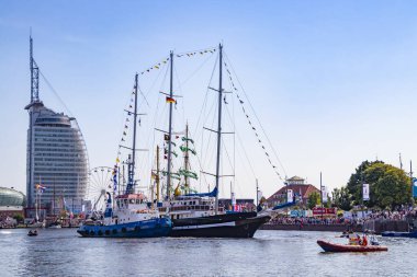 Güzel bir yelkenli gemisi Bremerhaven, Almanya 'nın merkezinde 13 Ağustos 2025' te gerçekleşen güzel yelkenli yarışı için bir römorkör tarafından iskeleye itilir.