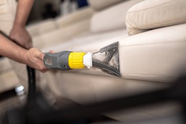 Kanepe yıkama makinesiyle kirli bir kanepeyi temizlemek. Kanepe temizleyicisi tutarken ellerinizi kapatın. Profesyonel kanepe yıkama, kanepe yıkama.