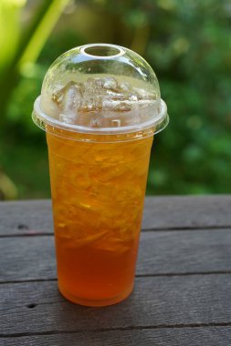 Chrysanthemum juice in plastic glass, on wooden floor background, blur nature background, food, drink, ice, cool, copy space                              