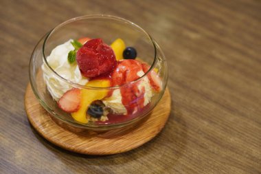  Çilekli dondurma tepeleme çilek dilimleri, yabanmersini, mango dilimleri ve ekmek kırıntıları, tahta tepside cam bir kavanoza koyun, ahşap arka planda, yemek, tatlı, kopyalama alanı                              