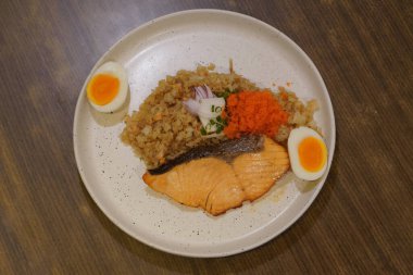 Üst manzara ızgara somon ve havyar, kızarmış pirinç ve ahşap masa arkasındaki seramik tabakta iki haşlanmış yumurta dilimi, yemek, sağlık, kopyalama alanı.       