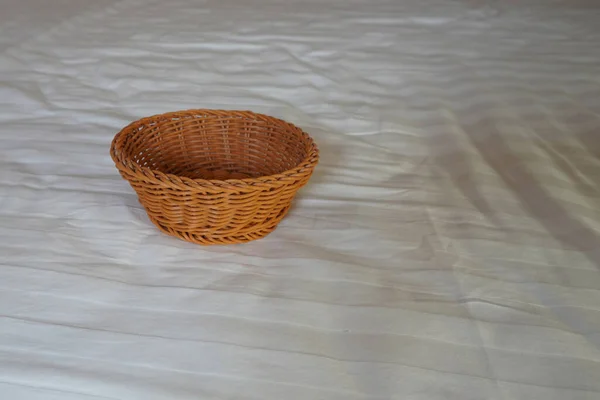 Kahverengi Hasır Sepet Beyaz Bir Yatak Örtüsü Üzerine Yerleştirilmiş Nesne — Stok fotoğraf