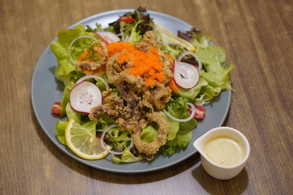 stock image caviar salad with fried calamari in a ceramic plate and mayonnaise sauce on wooden table background, food, nature, health, copy spac