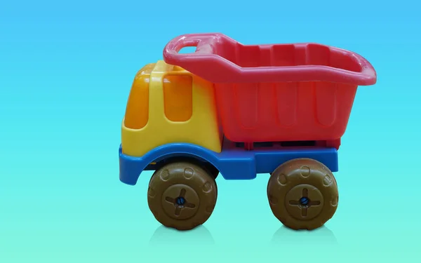 侧视图黄色 蓝色和绿色塑料卡车玩具渐变蓝色和绿色背景 复制空间 — 图库照片