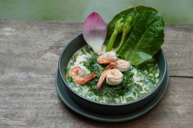 Yakın plan dört karides tabanlı hindistan cevizi çorbası gnetum gnemon yapraklı ve yeşil seramik tabakta karides, ahşap masa, bulanık doğa arka plan, yiyecek, doğa, kopyalama alanı