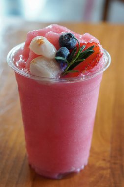 Tahta masada plastik bir bardakta liçi ve yaban mersinli çilekli smoothie, yiyecek, meyve, tatlı, buz, soğuk, kopyalama alanı                      