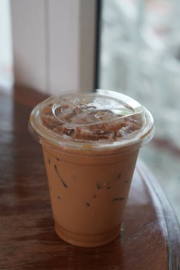 Tahta bir masaya yerleştirilmiş plastik bardaktaki Tayland çayı. Arka plan, içecek, buz, nesne, kopyalama alanı.                             