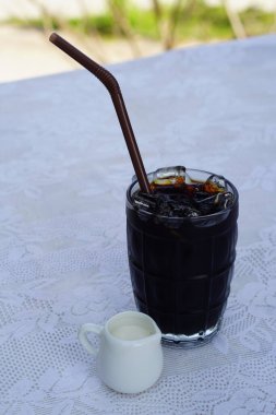 Tay kahvesi (Oliang) açık bir bardakta, kahverengi tüpte ve sütlü seramik bir bardakta, beyaz bir şişme örtüye yerleştirilmiş, arka planda, içecek, yiyecek, serinlik, kopyalama alanındadır.                            