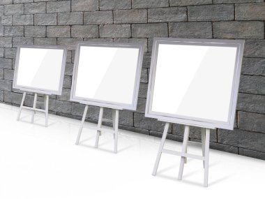 Siyah tuğla duvar zemininde, dekorda, nesnede, beyaz kağıtta, kağıtta, posterde, kopyalama alanındaki beyaz ahşap bir standın üzerinde uzun bir sıra halinde dizilmiş üç resim çerçevesi.