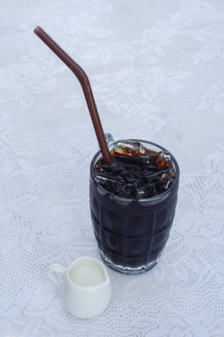 Üst Manzaralı Tayland Kahvesi beyaz kumaş arka planı, içecek, yiyecek, soğuk, kopyalama alanı üzerinde küçük bir seramik bardakta, kahverengi bir tüp ve süt içerir.                                