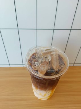 En üstteki karamelli kahve plastik bir fincanda, beyaz fayans duvarı arka planda, içecek, yiyecek, moda, kopyalama alanı