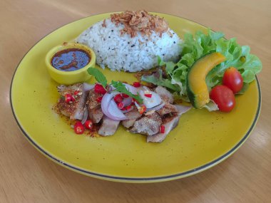 Tayland yemeği, şelale domuzu, pirinç ve Vietnam sarımsağı sarı bir kase içinde, yeşil sebze, 1 parça balkabağı, 2 parça domates ahşap arka planda, yemek, kopyalama alanı