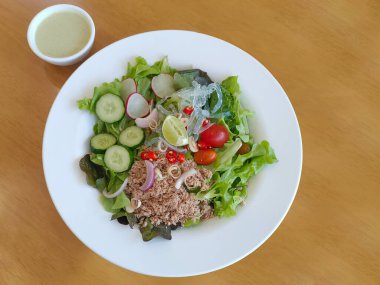 Beyaz tabakta ton balığı salatası ve masada salata sosu, yemek, sebze, fotokopi alanı.