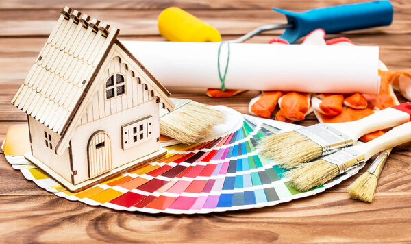 Model of house with work tools and color swatches book. on the wooden table. Home repair and improvement concept.