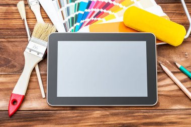 İçinde renk örnekleri olan boş bir tablet, tablo üzerinde boya fırçası ve boya silindiri. Boşluğu kopyala.
