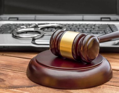 Gavel dizüstü bilgisayarı ve kelepçeleri tahta masada..