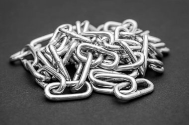 Siyah zemin üzerinde metal zincir yığını.