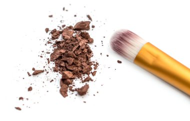 Beyaz arka planda ezilmiş göz gölgeleriyle makyaj fırçası.