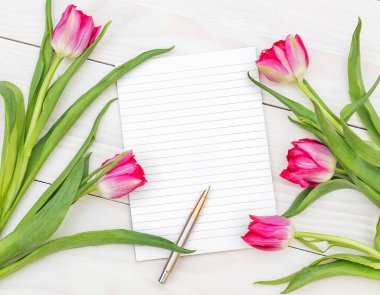 Boş not defteri ve ahşap masa üzerinde Lale ile buket. Üstten Görünüm.