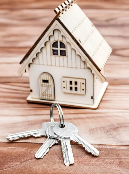 Keys with model of house on the wooden background. Real estate concept.