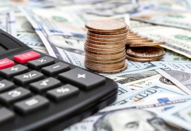 Dolar banknotlarının arka planında bozuk paralar olan hesap makinesi. İş konsepti.