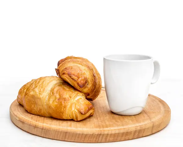 Stock image Cutting board with cup of coffee and two croissants on the table. Isolated on white.