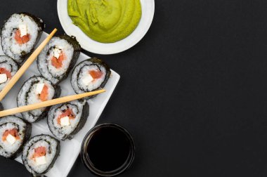 Soya soslu suşi ve yemek çubukları ve siyah arka planda wasabi. Üst görünüm.