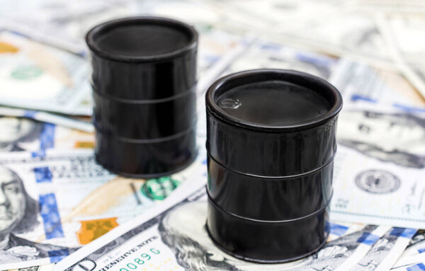 Две баррели сырой нефти на фоне долларовых купюр.