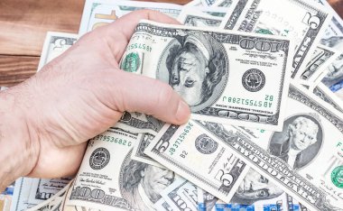 Adamın eli para dolu dolarları masanın üzerinde tutuyor..