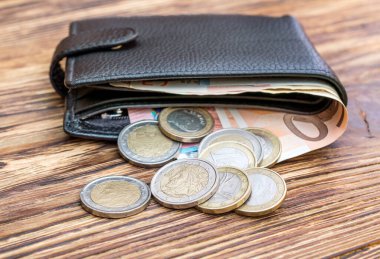 Avro banknotları ve ahşap masanın üzerinde avro paraları olan cüzdan. İş konsepti.