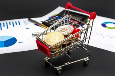 Siyah arka planda bitcoin, hesap makinesi ve iş grafikleri olan alışveriş arabası. İş ve mali konsept.