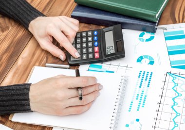 İş kadını, iş yerindeki şirket mali endekslerini hesaplamak için hesap makinesi kullanır. İş konsepti.