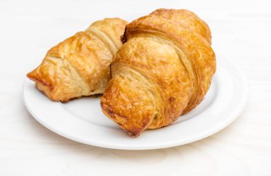 Beyaz ahşap masada iki kruvasan tabağı. Kapat..