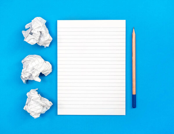 Crumpled notepad sheets with pencil on blue. Writing and creativity concept.