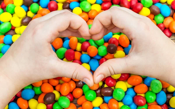 Ręce Dziecka Pokazujące Gest Serca Nad Kolorowymi Cukierkami Obrazek Stockowy