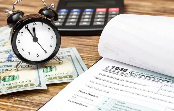 Tax form  with money, clock and calculator on the desk.