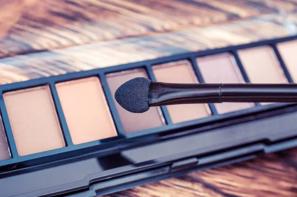 Makyaj için fırça ve ahşap arka planda göz farı. Tonu ayarlanmış resim.