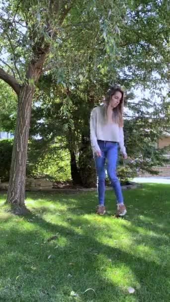 公園で庭の木の幹にジャンプかわいい国内猫と遊んで若い女性の垂直ビュー — ストック動画