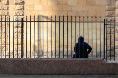 Back view of unrecognizable arab traditional woman with Hijab on, sitting on the edge of a curbstone in the street of Cairo, Egypt, Africa