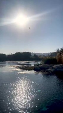 Egypt landscape with sand dunes, vegetation and rocky river bank view from a boat with blue sky
