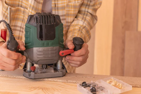 stock image High angle of crop workman using electric router machine while working with wood in carpentry workshop