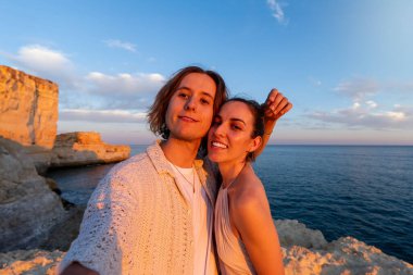 Bir Aşk Anı: Güneş batımında Portekiz 'de, Rocky Cliff' te kucaklaşan ve gülümseyen bir çiftin yakın çekim, yatay görüntüsü.